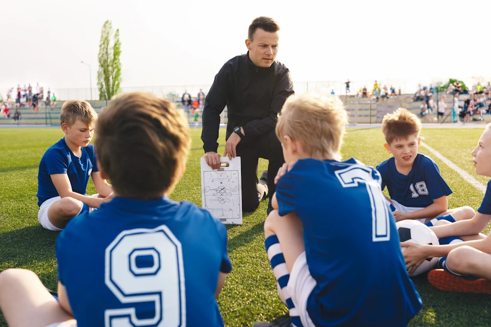 Fotbollscoach som går igenom strategi med en bunt ungdomar